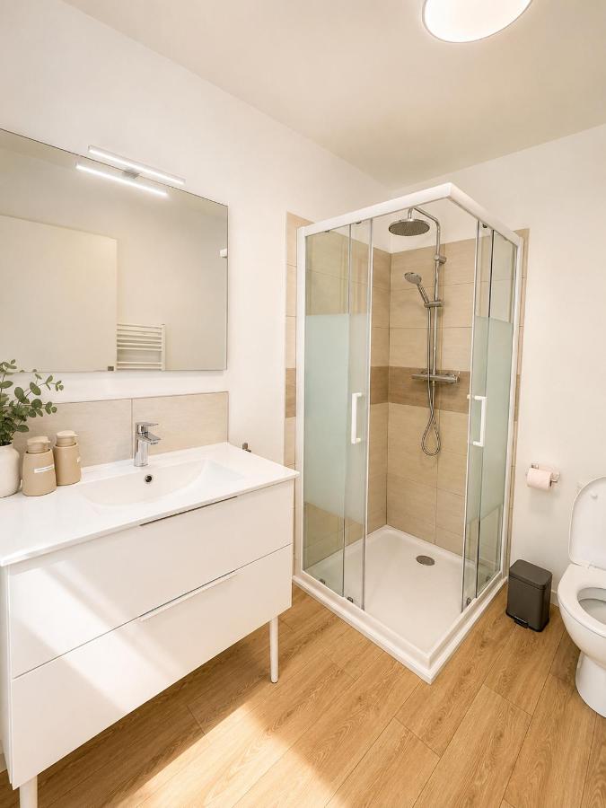 Salle de bain claire avec grand lavabo, miroir et cabine de douche d'angle